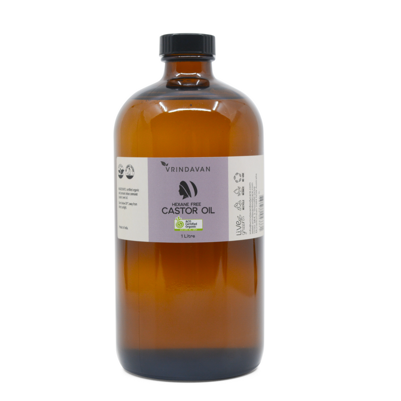 A 1L amber glass bottle of certified organic castor oil with a label showing the brand and product name.